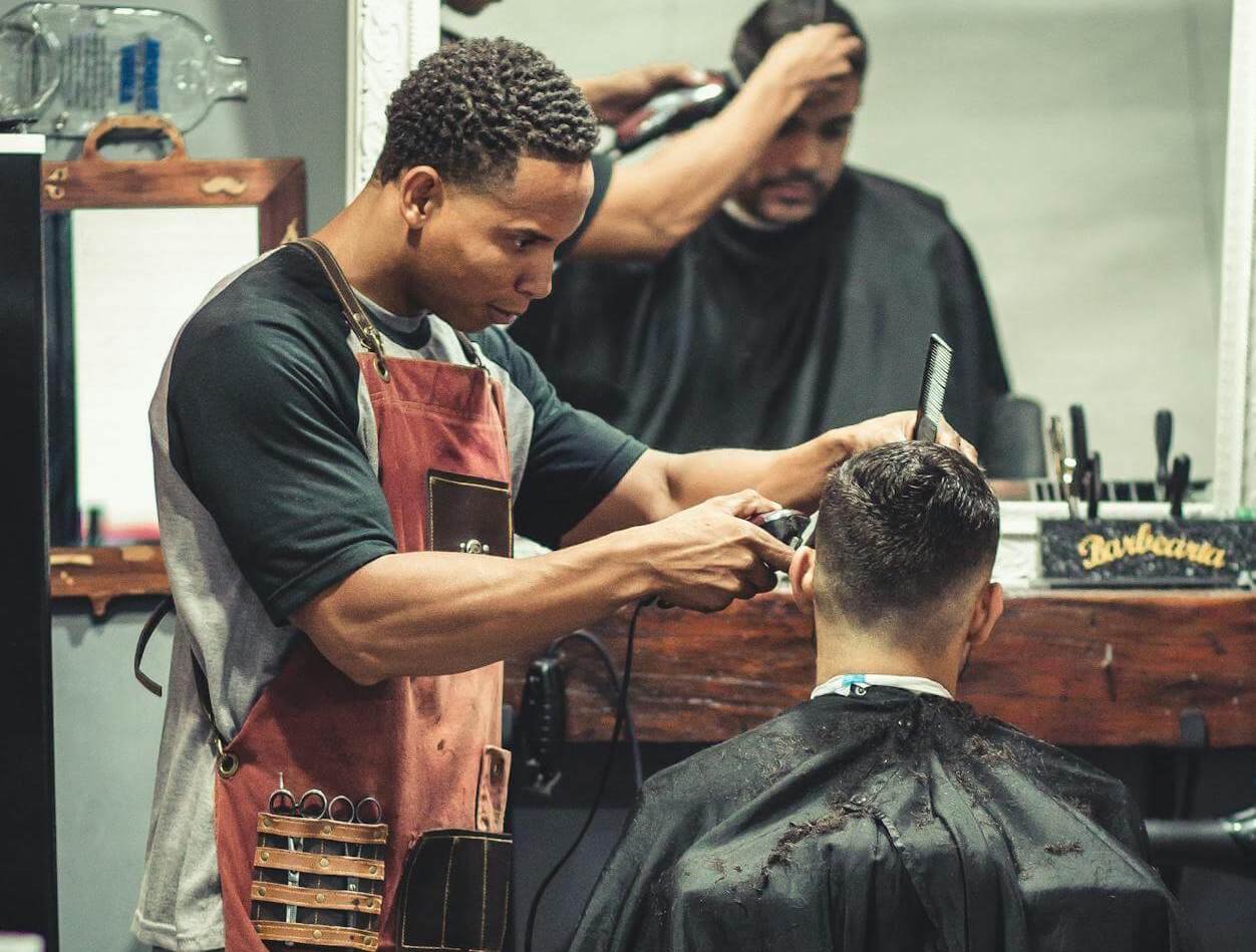 Bild på en frisör som klipper en man med taper fade.